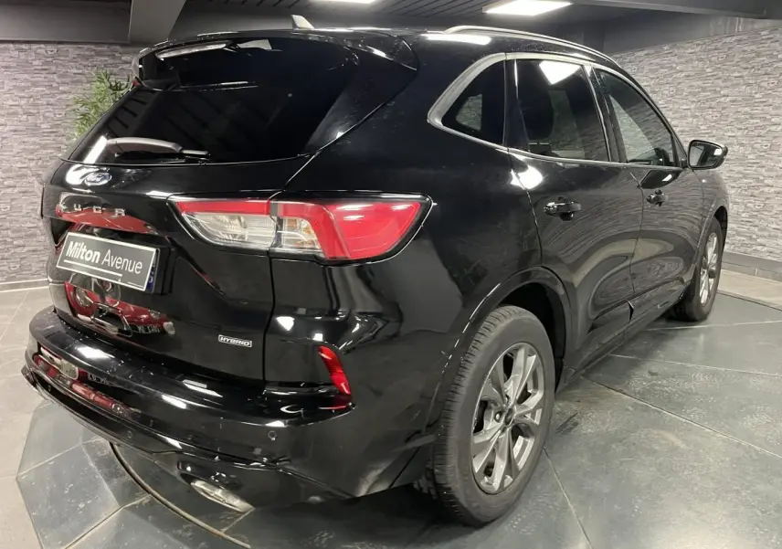 Vue 3/4 arrière droite d'un Ford Kuga noir hybride avec feux arrière LED et jantes alliage 18 pouces.