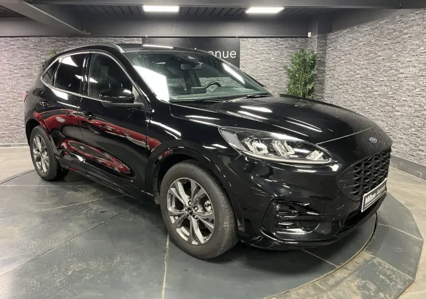 Ford Kuga noir en 3/4 avant droit, avec calandre large et jantes alliage 18 pouces ST-Line visibles.