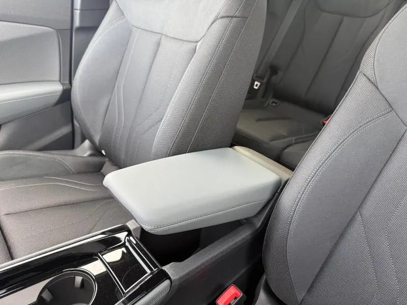 Vue rapprochée de l’intérieur de l’Audi Q3 2026, montrant les sièges avant gris foncé et l’accoudoir central.