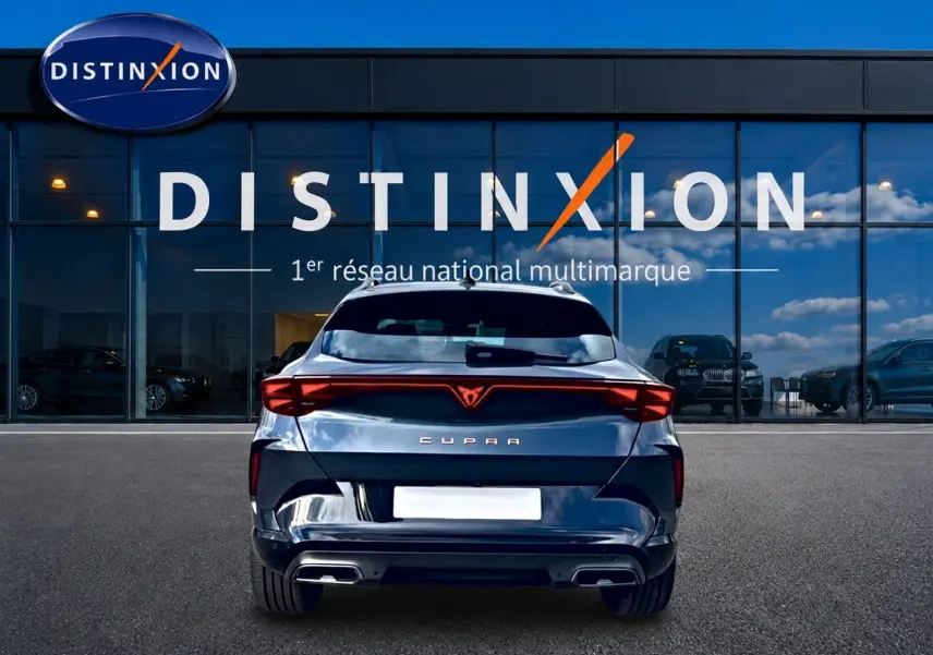 Vue arrière d'une CUPRA Formentor gris magnétique 2026 avec feux LED et double sortie d'échappement, devant une vitrine Distinxion.