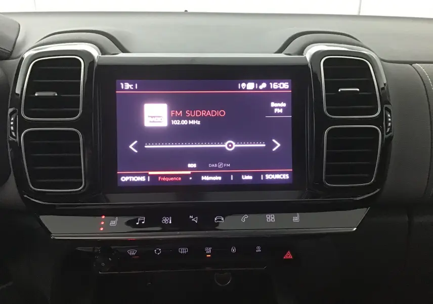 Écran tactile central allumé du Citroën C5 Aircross gris, affichant la radio FM Sudradio à 16h06, entouré de commandes noires.