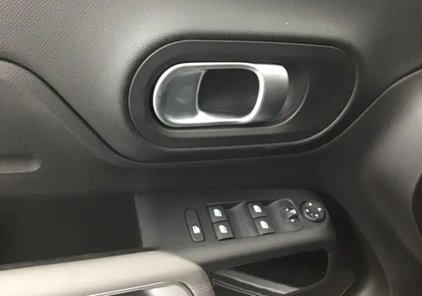 Gros plan sur la poignée de porte intérieure et les commandes des vitres côté conducteur du Citroën C5 Aircross 2021 finition Feel Pack.