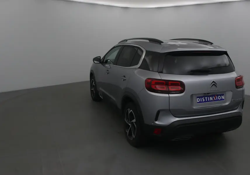 Vue 3/4 arrière droite d'un Citroën C5 Aircross gris Artense avec vitres teintées et jantes noires.