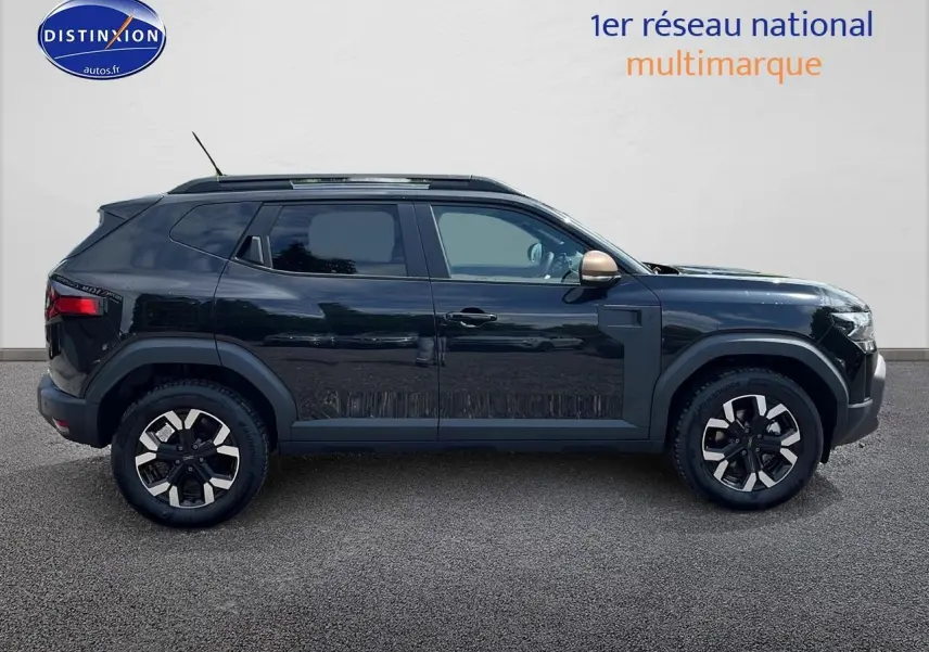 Profil droit du Dacia Duster noir 2025 avec jantes alu et barres de toit visibles sur fond neutre.