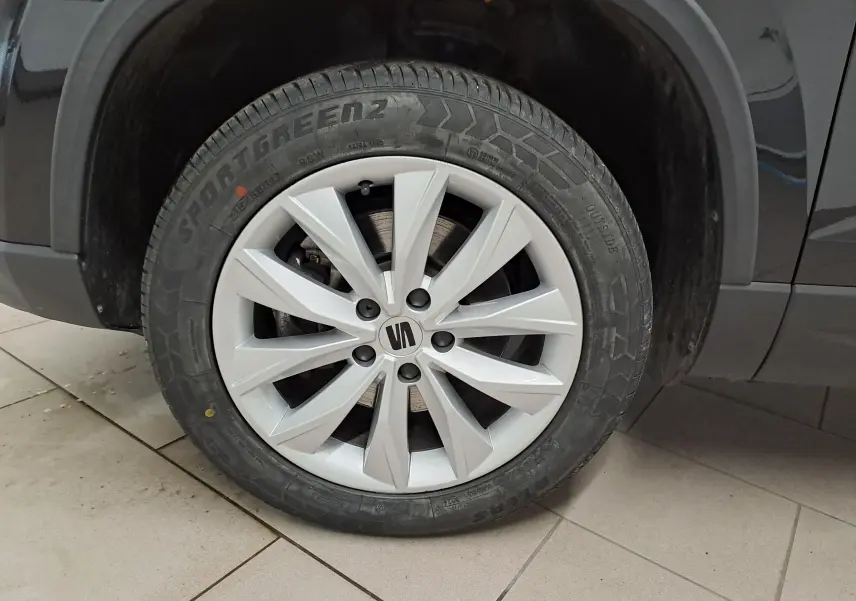 Gros plan sur la roue avant droite d’un SEAT Ateca noir Minuit, jante argentée à dix branches.