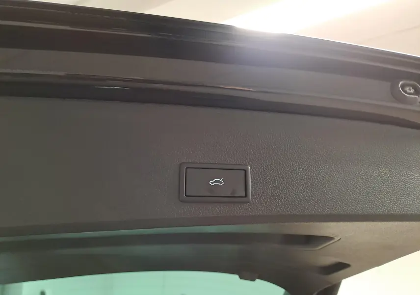 Bouton d'ouverture électrique du hayon sur la partie intérieure du coffre d'un SEAT Ateca Noir Minuit, vue rapprochée.