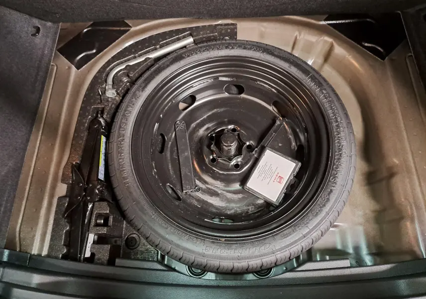 Vue plongeante sur la roue de secours noire et le cric dans le coffre du SEAT Ateca 2023 Noir Minuit.