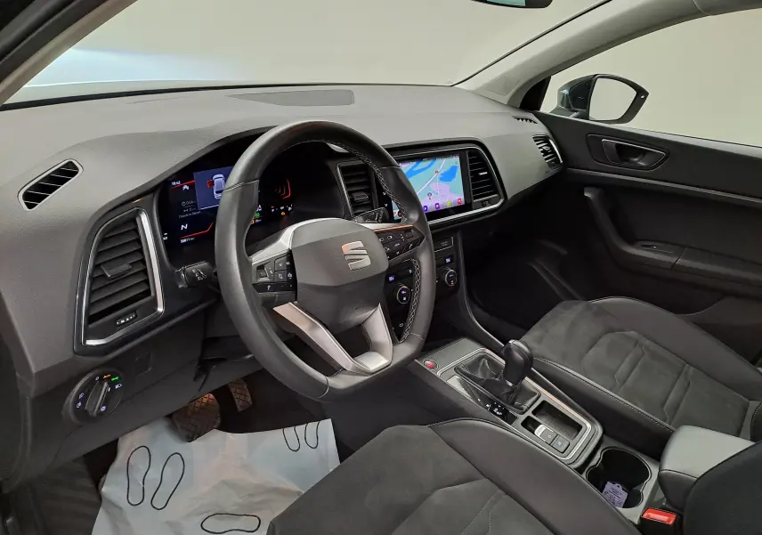 Vue intérieure côté conducteur du SEAT Ateca 2023, sellerie suédine noire, tableau de bord noir Titane avec écran tactile central.