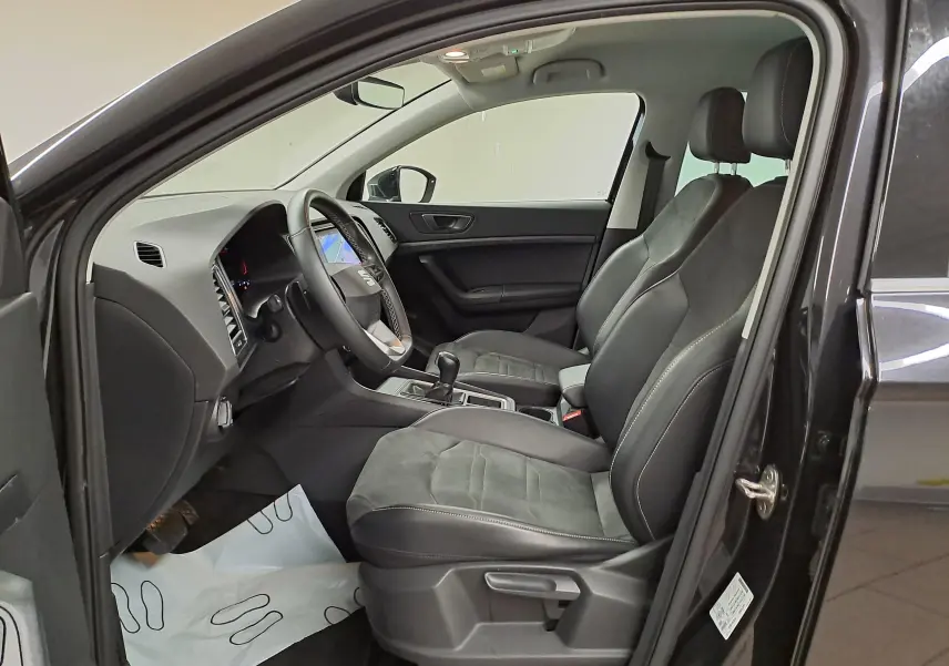 Vue intérieure côté gauche du SEAT Ateca 2023 noir Minuit, mettant en valeur les sièges en suédine noire et tableau de bord noir Titane.