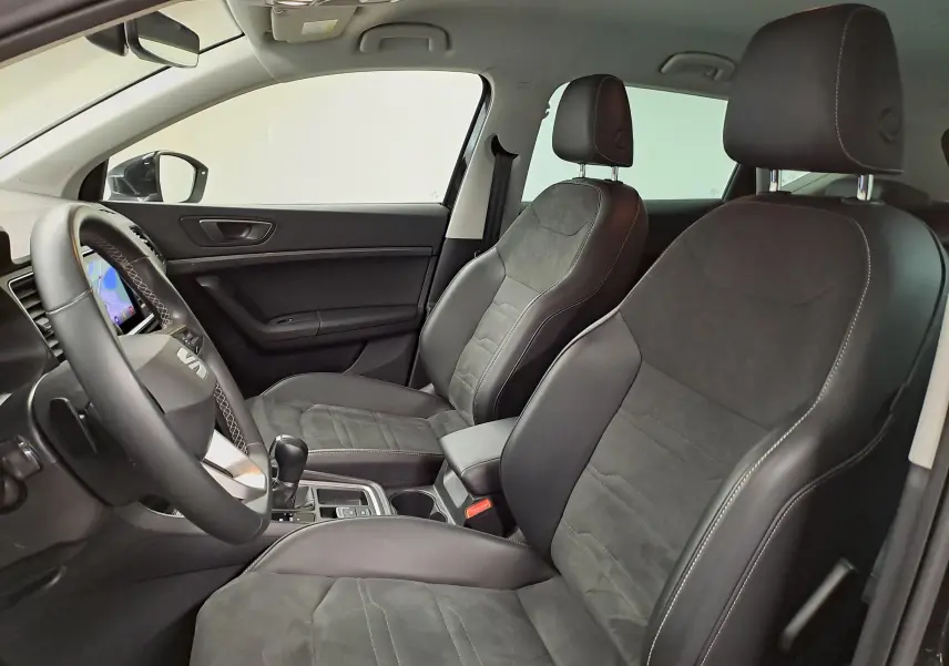 Vue intérieure côté conducteur du SEAT Ateca 2023 avec sellerie suédine noire et surpiqûres grises, tableau de bord noir Titane.