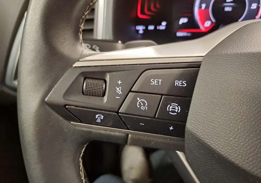 Gros plan sur les commandes au volant côté gauche du SEAT Ateca 2023 Noir Minuit, avec régulateur de vitesse adaptatif.