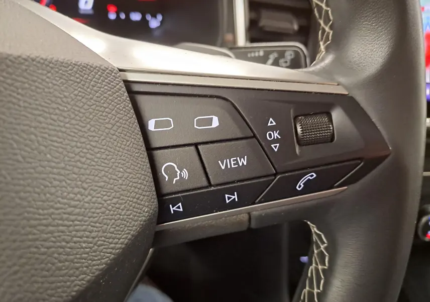 Gros plan sur les commandes multifonctions noires à gauche du volant du SEAT Ateca 2023 Noir Minuit.