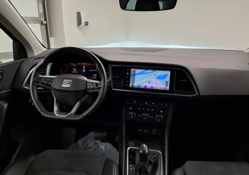 Vue intérieure avant du tableau de bord et volant noir du SEAT Ateca 2023 avec écran tactile et sellerie suédine noire.
