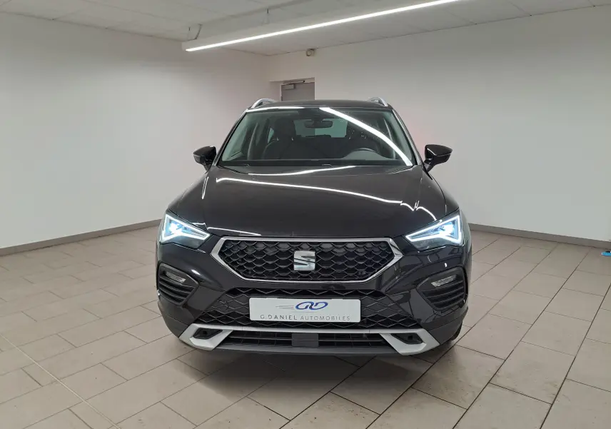 Vue frontale d'un SEAT Ateca 2023 noir minuit avec feux LED allumés dans un showroom intérieur.