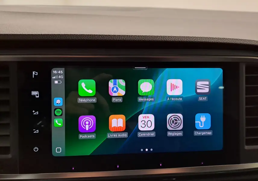 Écran tactile central du SEAT Ateca 2023 affichant l'interface Apple CarPlay avec icônes colorées sur fond noir.