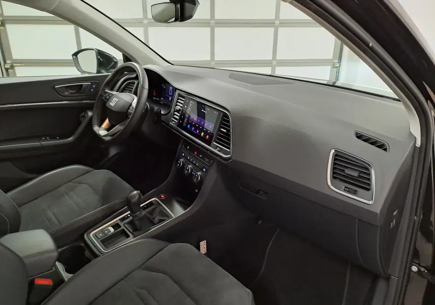 Vue intérieure côté conducteur du SEAT Ateca Noir Minuit 2023, sellerie suédine noire et tableau de bord noir Titane avec écran tactile.