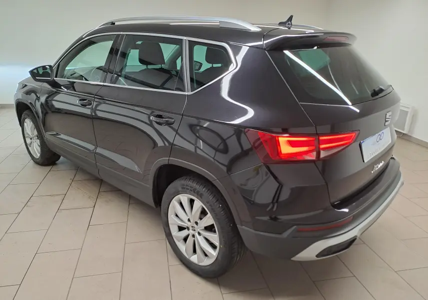 Vue 3/4 arrière droite du SEAT Ateca 2023 noir minuit avec feux arrière allumés et jantes alliage.