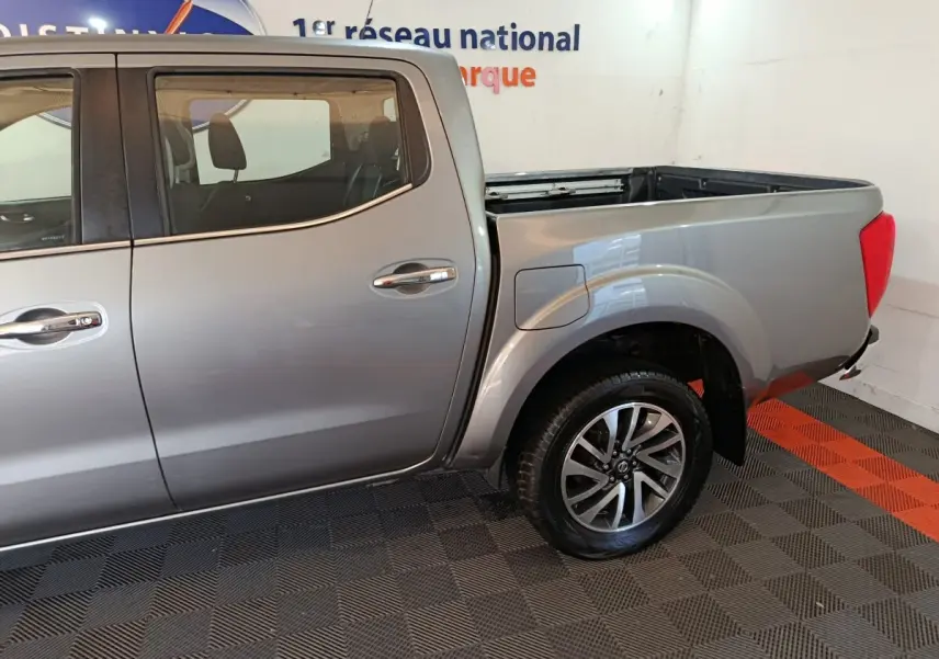 Vue latérale droite du Nissan Navara Double-Cab gris clair, mettant en valeur la benne pick-up et la roue arrière avec jante alliage.