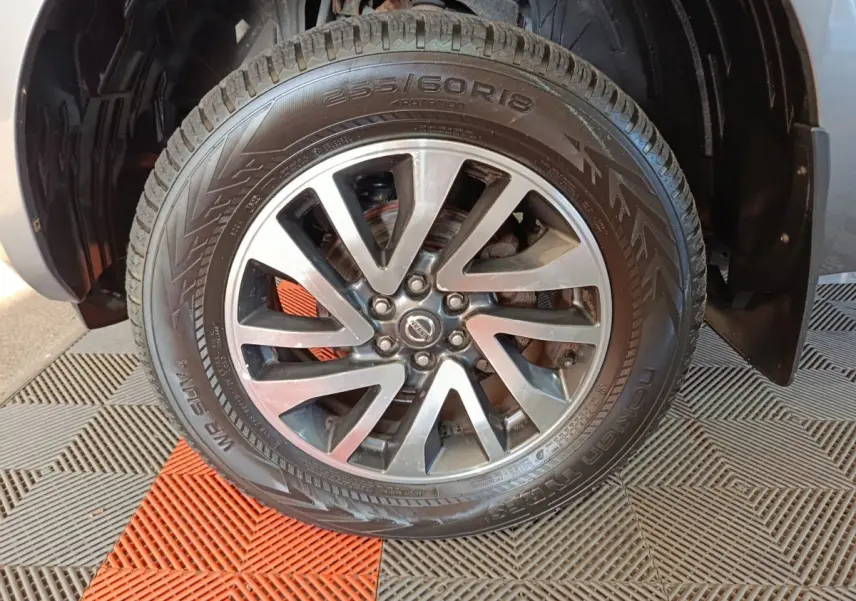 Gros plan sur la roue avant droite du Nissan Navara gris clair, mettant en valeur la jante alliage et le pneu Nokian.