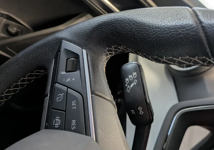 Gros plan sur le volant en cuir noir avec commandes intégrées côté gauche dans l’habitacle d’une SEAT Ibiza blanche.