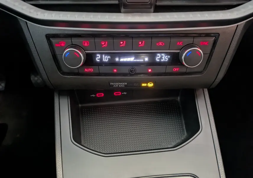 Gros plan sur la console centrale de la SEAT Ibiza 2022, montrant la climatisation automatique avec affichage digital et commandes rouges.
