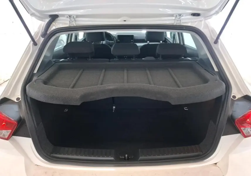 Vue 3/4 arrière droite d'une SEAT Ibiza blanche 5 portes, berline compacte exposée en showroom.