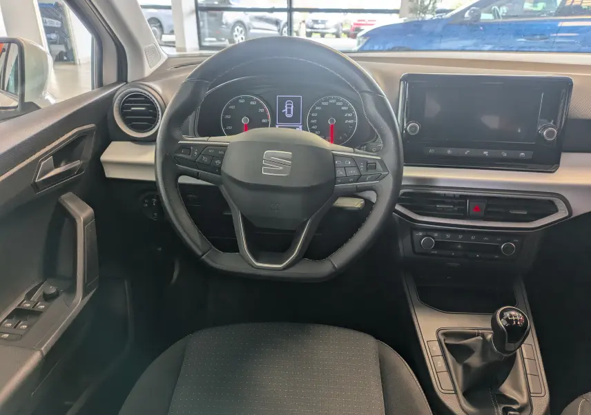 Vue intérieure frontale du poste de conduite de la SEAT Ibiza blanche 2022 avec volant multifonction et boîte manuelle.