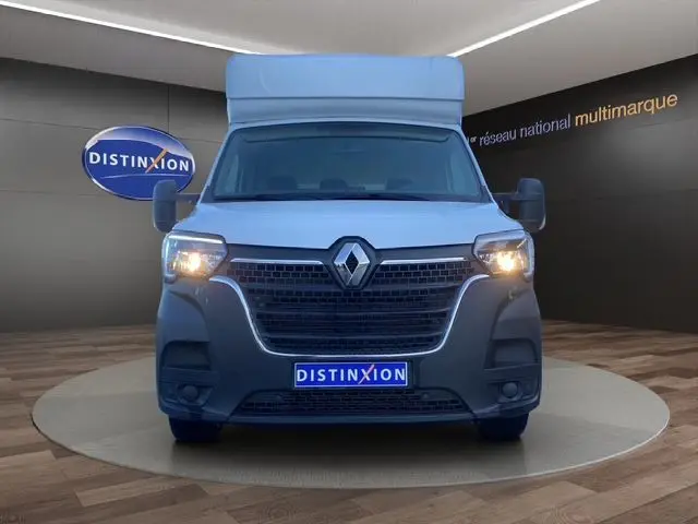 Vue frontale d’un Renault Master blanc 2022 avec calandre noire et phares allumés, présenté en showroom Distinxion.