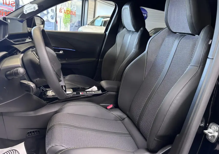 Vue intérieure côté conducteur du Peugeot 2008 1.2i Hybrid 2026, sièges tissu et cuir noir avec surpiqûres vertes.
