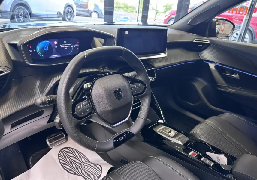Vue intérieure côté conducteur du Peugeot 2008 GT 2026, tableau de bord noir avec écran tactile et volant compact cuir.
