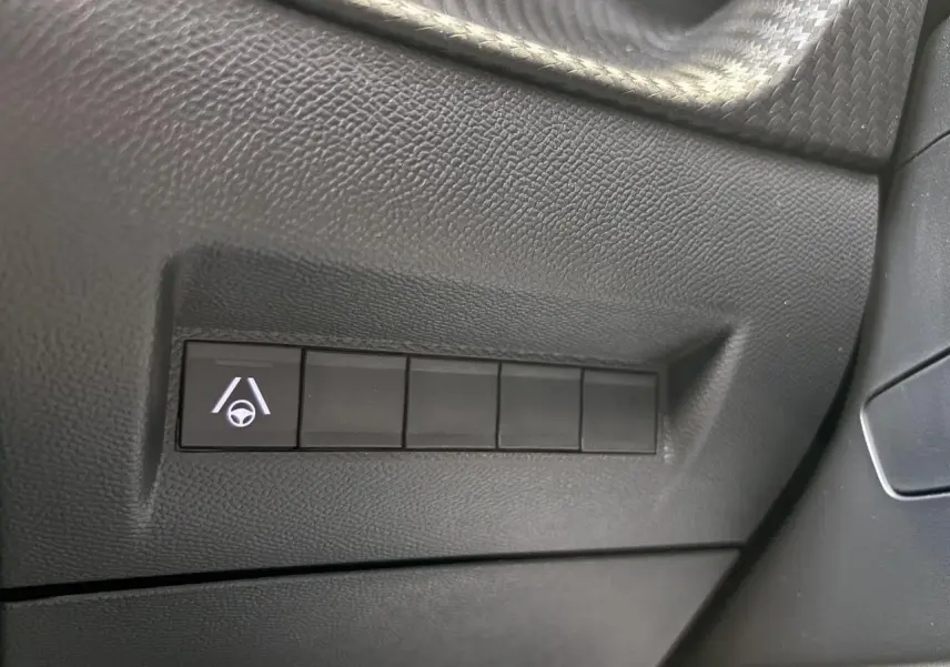 Gros plan sur bouton d’aide au maintien dans la file sur tableau de bord noir du Peugeot 2008 hybride 2026.