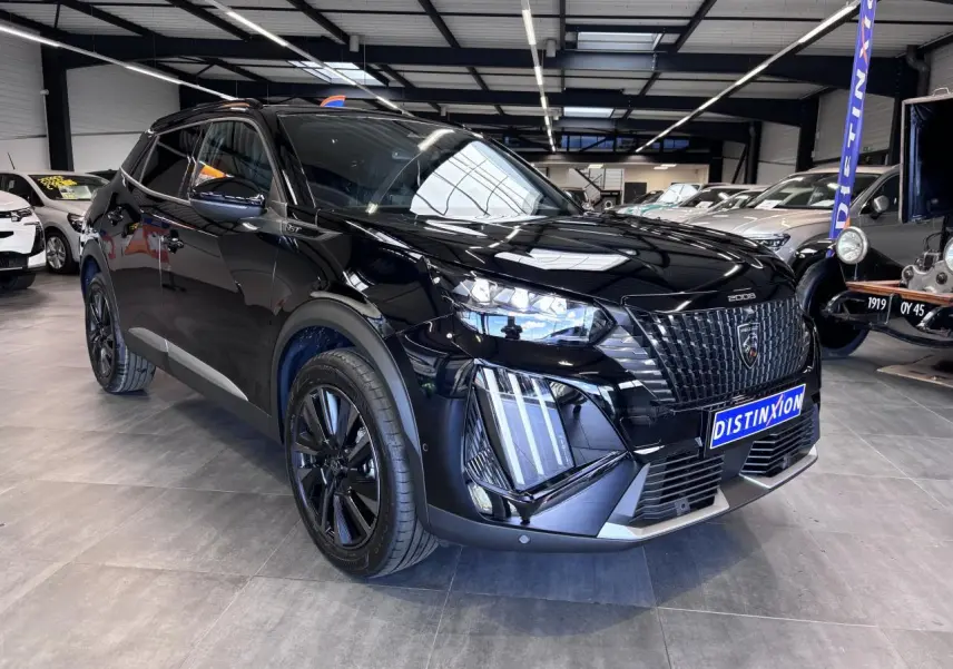 Peugeot 2008 noire vue 3/4 avant en intérieur, avec calandre noire distinctive et jantes alliage noires.