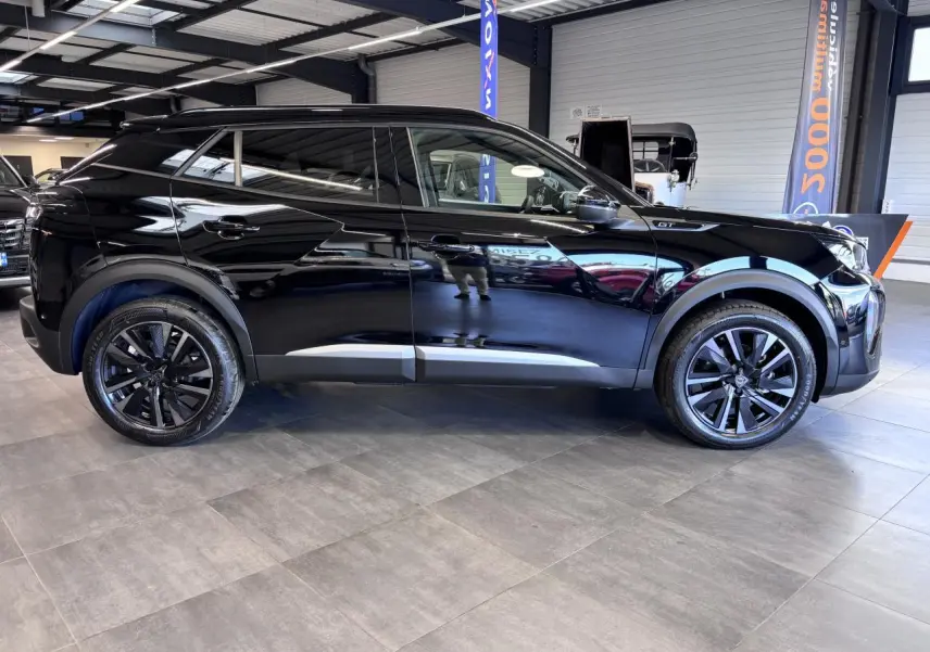 Profil droit d’un Peugeot 2008 noir brillant avec jantes alliage bi-ton 18’’ dans un showroom intérieur.