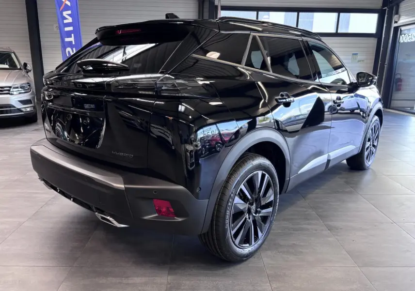 Vue 3/4 arrière droite d'un Peugeot 2008 noir brillant avec jantes alliage bi-ton et toit noir en showroom.