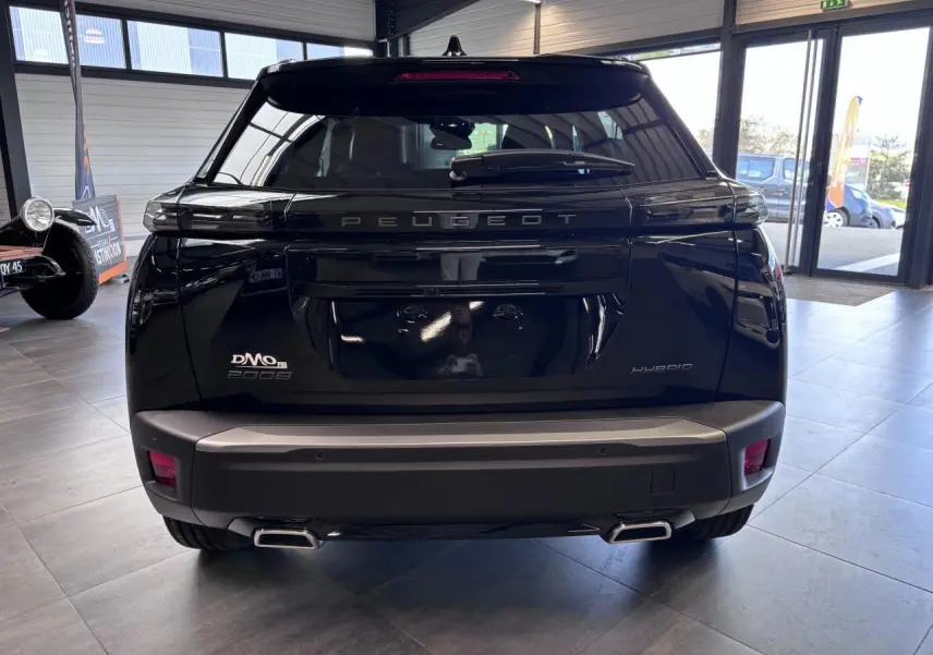 Vue arrière d'un Peugeot 2008 hybride noire, avec double sortie d'échappement et logo PEUGEOT en relief sur le hayon.
