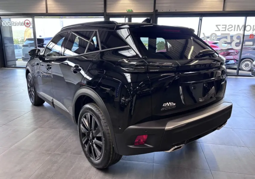 Vue 3/4 arrière droite d'un Peugeot 2008 noir brillant avec jantes alliage 18'' bi-tons dans un showroom.