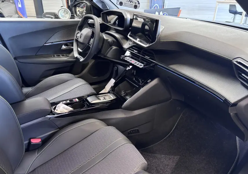Intérieur avant droit du Peugeot 2008 1.2i Hybrid 2026, avec tableau de bord noir et écran tactile 10 pouces.