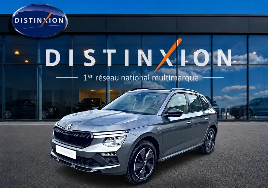 Skoda Kamiq gris graphite en 3/4 avant droit, avec jantes alu noires et toit panoramique visible.