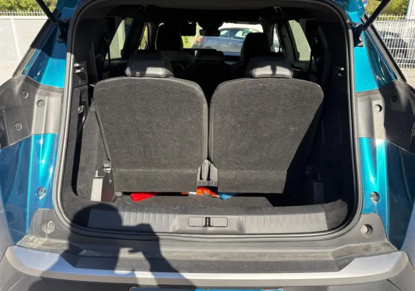 Coffre ouvert vu de l'arrière d'un Peugeot 5008 Hybrid bleu foncé 2025, avec sièges arrière relevés.