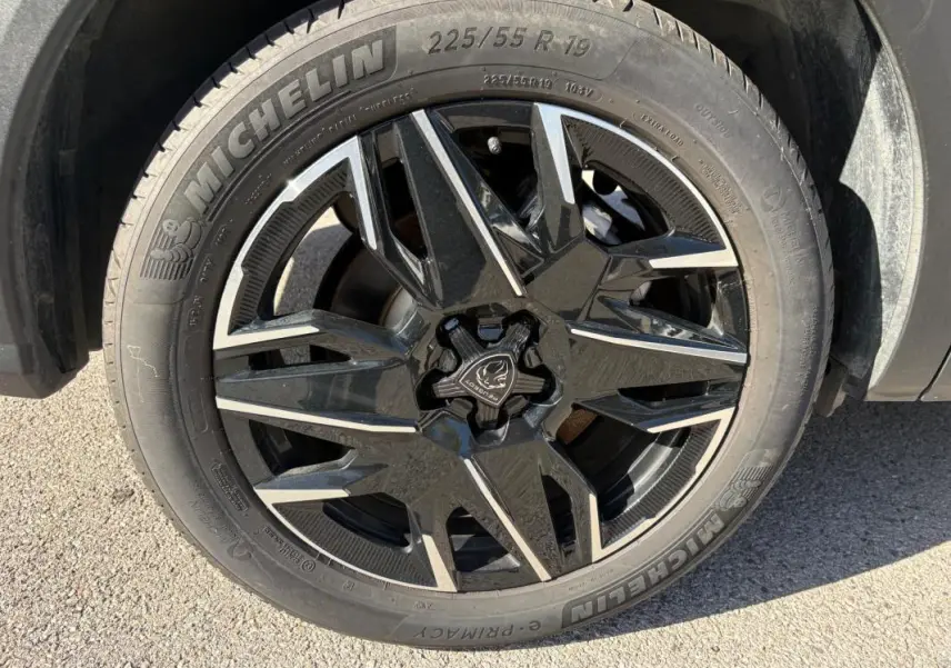 Gros plan sur la roue avant droite du Peugeot 5008 bleu foncé 2025, jante noire à motifs géométriques distinctifs.