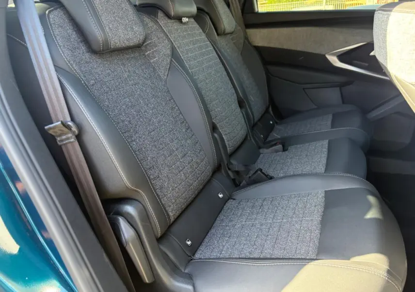 Vue latérale droite des sièges arrière en tissu gris et cuir noir du Peugeot 5008 Hybrid 2025 bleu foncé, finition Allure.