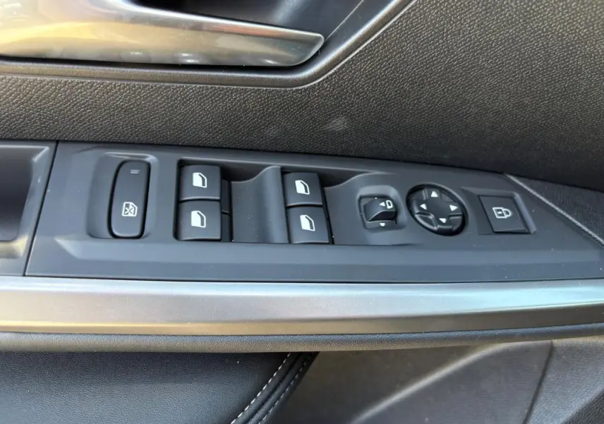 Gros plan sur les commandes de lève-vitres et rétroviseurs côté gauche d’un Peugeot 5008 bleu foncé 2025 Hybrid Allure.