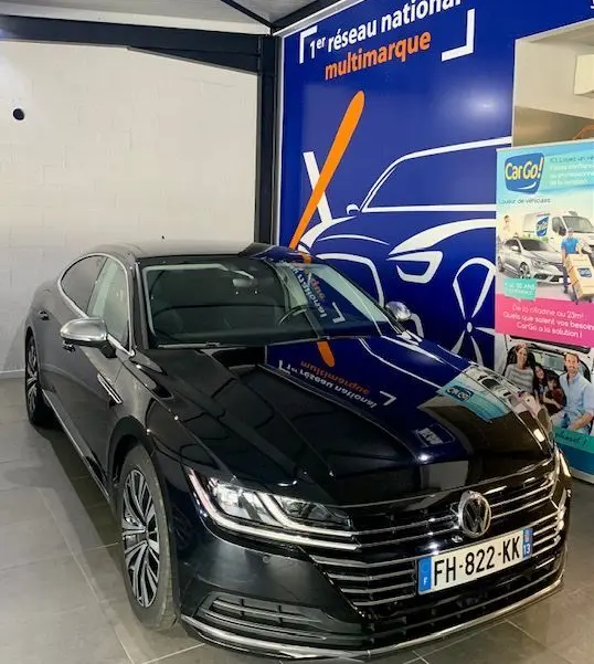 Volkswagen Arteon noir 2019 en 3/4 avant droit, avec calandre chromée et phares LED allumés dans un showroom.