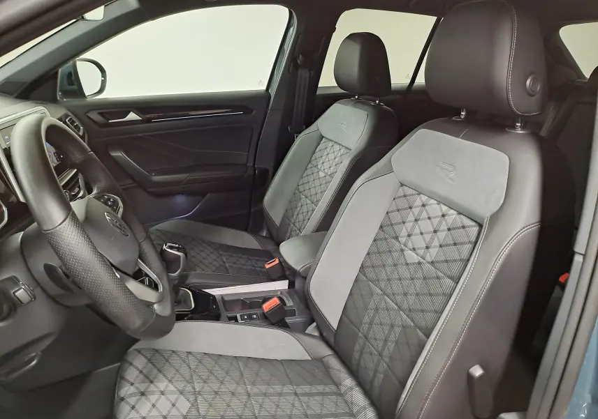 Vue intérieure côté conducteur du Volkswagen T-Roc 1.5 TSI R-Line avec sièges en tissu et cuir gris, volant multifonction.