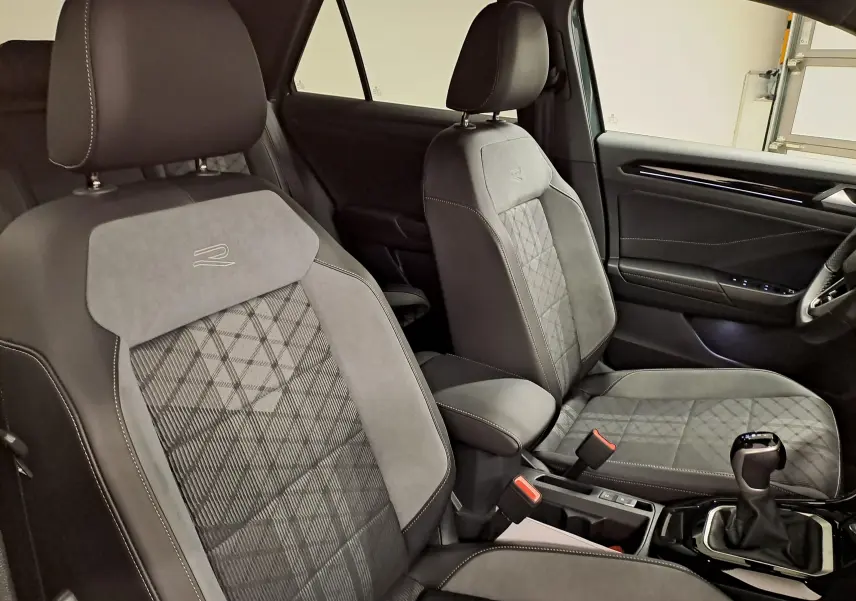 Vue intérieure du Volkswagen T-Roc 1.5 TSI R-Line Edition montrant les sièges avant en tissu et cuir gris avec surpiqûres contrastées.