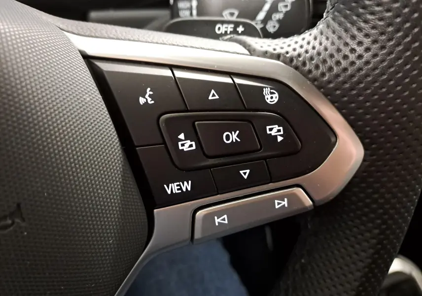 Gros plan sur les commandes multifonctions du volant perforé du Volkswagen T-Roc 1.5 TSI 150 DSG7 R-Line Edition.