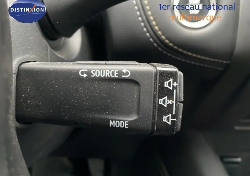 Gros plan sur la commande au volant noir étoile métal de la Renault Symbioz 2025, avec boutons source et mode visibles.