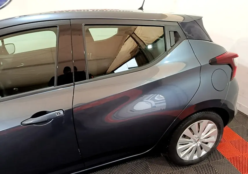 Vue latérale côté droit d'une Nissan Micra gris foncé, mettant en valeur la ligne fluide et la jante alliage arrière.