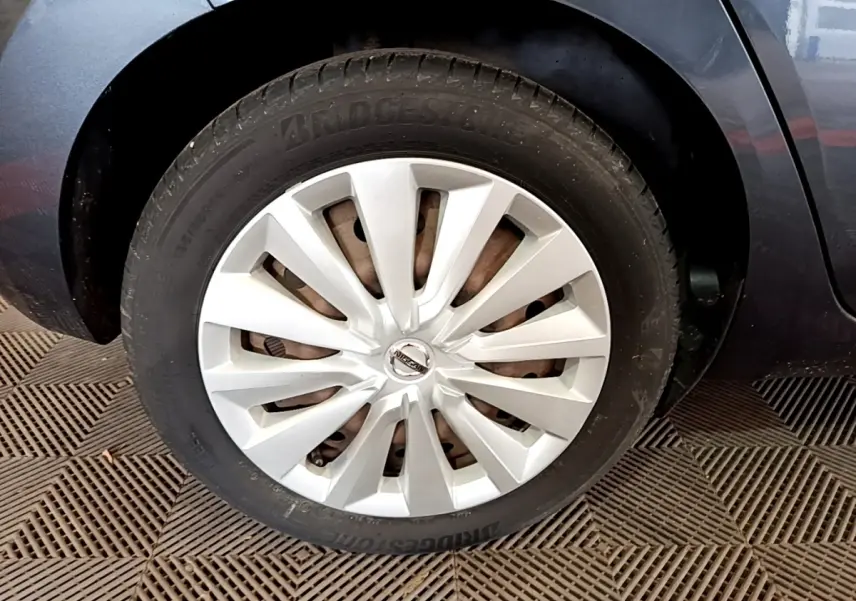 Gros plan sur la roue avant droite d’une Nissan Micra gris foncé avec jante argentée en étoile.