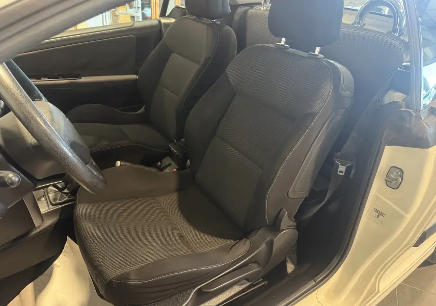 Vue intérieure côté conducteur du cabriolet beige Peugeot 207 CC 2007, sièges noirs et volant visible.